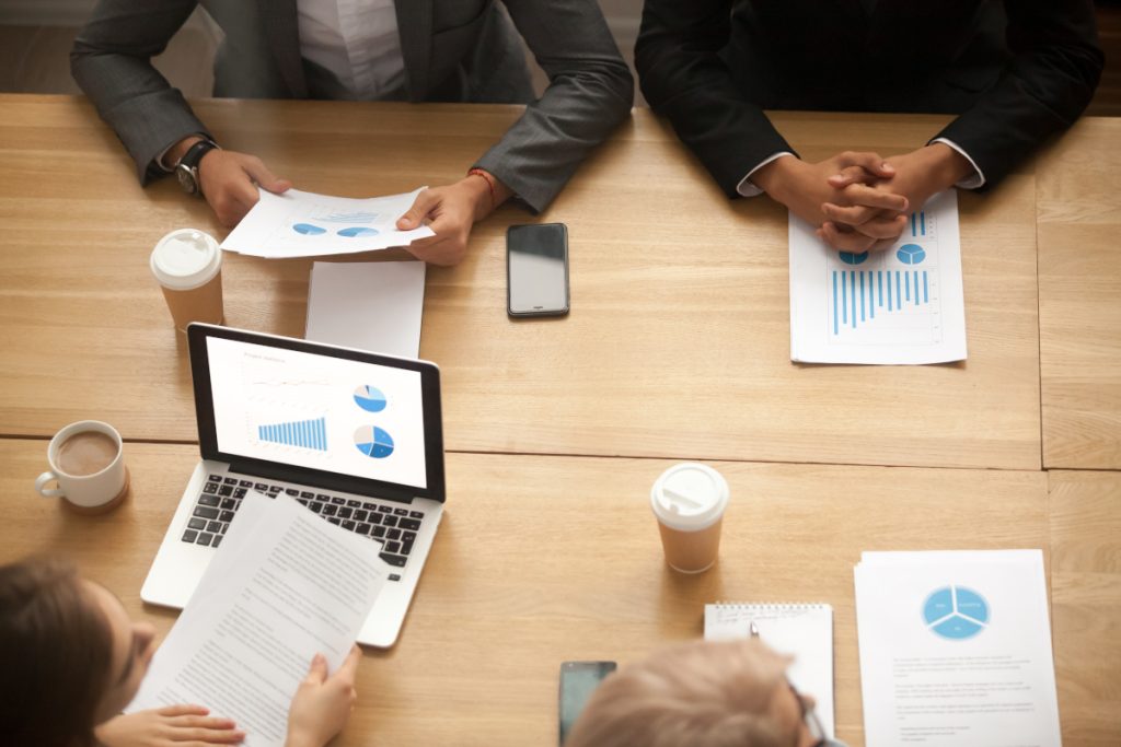 Business team brainstorming analyzing statistics report at meeti Business team brainstorm on new marketing plan analyzing statistics at group meeting, businesspeople working together on project report with financial results, teamwork concept, top view from above